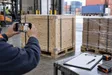 Warehouse professional photographing a packed wooden crate before international freight transport.