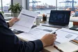Import operations professional reviewing freight documents and a shipment route before booking.